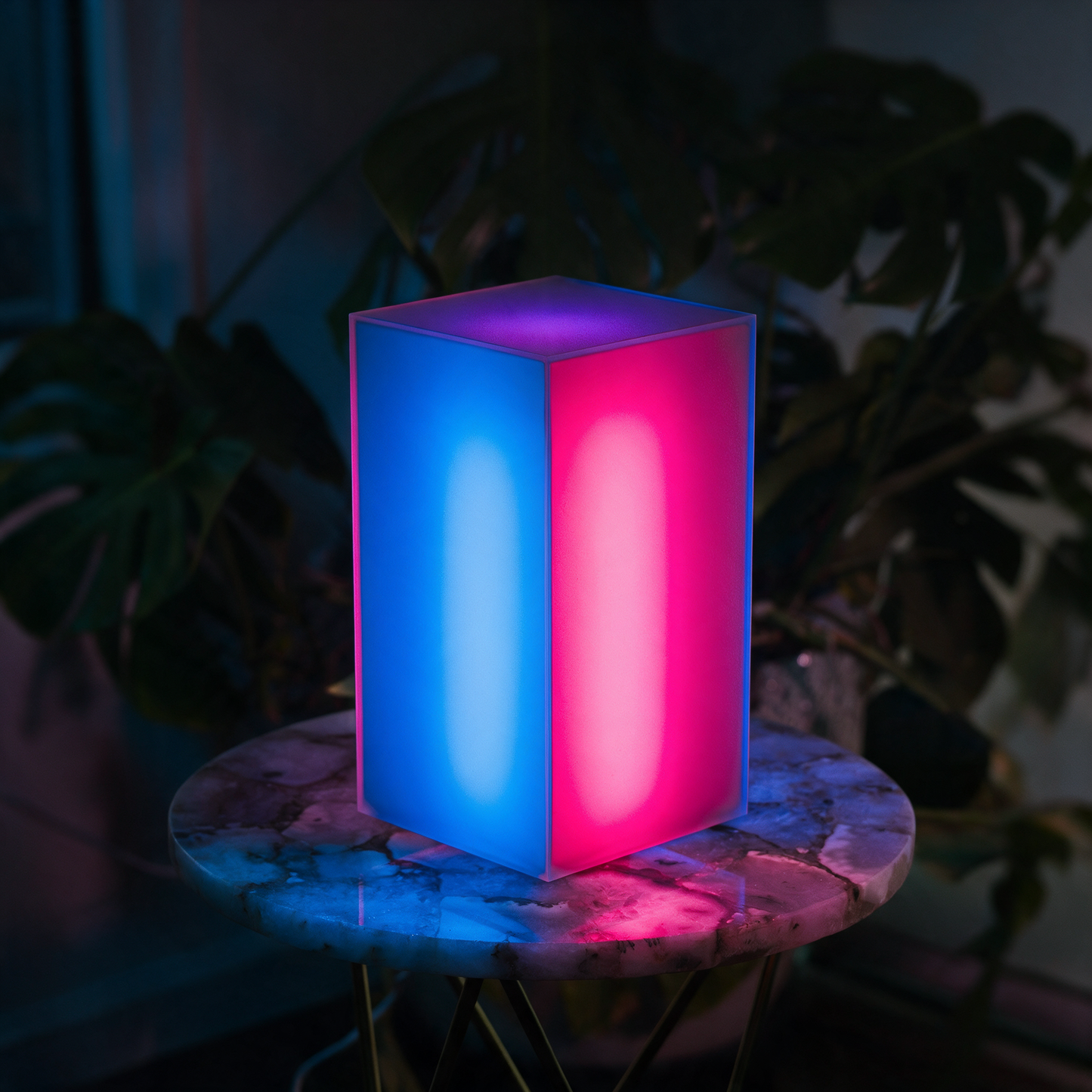 Lumen smart LED lamp glowing blue and pink in a dark room